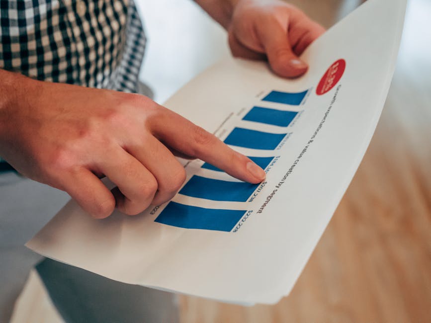 Close-up of hands pointing at a bar chart on paper, analyzing financial stats and report